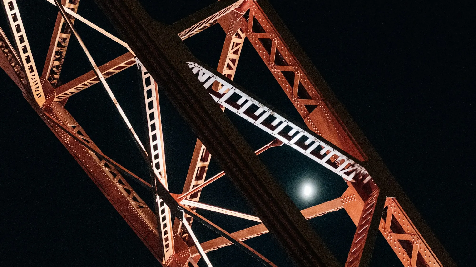 Steel truss bridge structure lit against a night sky